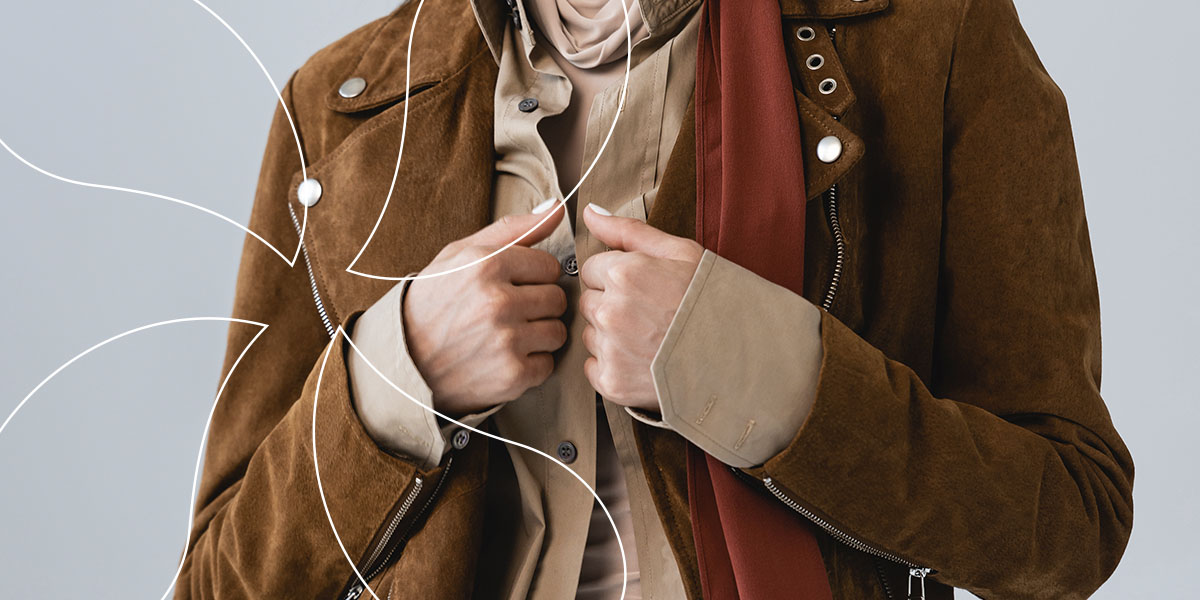 person grabbing their brown suede leather jacket