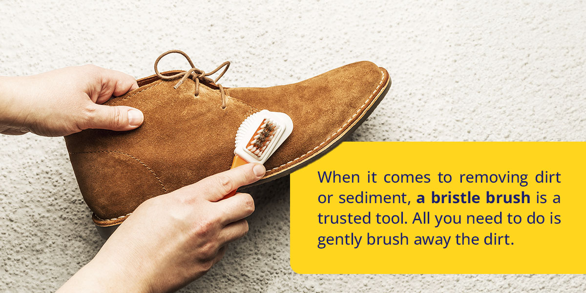 hands brushing a brown suede shoe